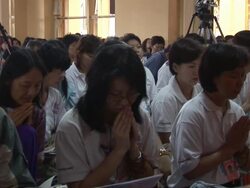 MS People sitting on ground with their hands folded in prayer listening to someone speak Stock Footage