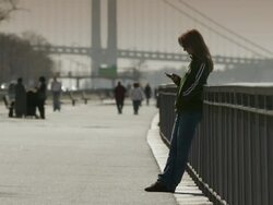 A women types on her cell phone, the Verrazano bridge is behind. Stock Footage