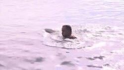 Sunbathers enjoy warm weather on a beach close to Winter Games venue News Clip