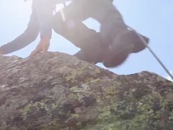 Mountaineer ascends mountain ridge, coils rope Stock Footage