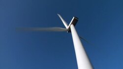 The blades of a wind turbine spin against the blue sky. Stock Footage