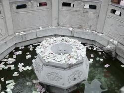 CU ZO TU Pilgrims circle round wishing well to touch stone lion and drop money pray for good luck during Chinese Lunar New Year at Taoist temple / xi'an, shaanxi, china Stock Footage