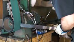 Knife maker grinding down edges on blade Stock Footage