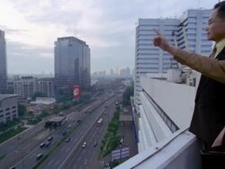 Wide shot pan two Asian businessmen talking and pointing from rooftop over highway Stock Footage