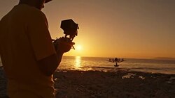 Man operating drone from beach at sunset Stock Footage