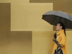 MS Young woman holding umbrella walking past yellow wall/ China Stock Footage
