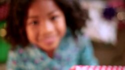Cute young girl with Christmas present looks up and smiles at camera Stock Footage