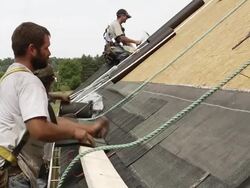 MS Shot of three workers hammering on roof of red building / Chelsea, Michigan, United States Stock Footage