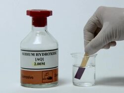 Universal indicator paper being dipped in sodium hydroxide, a strong alkali. Universal indicator turns purple in the presence of alkalis Stock Footage