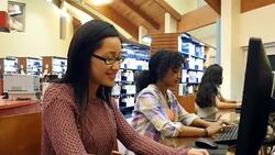 Young Asian female college student works on assignment at desktop computer in library Stock Footage