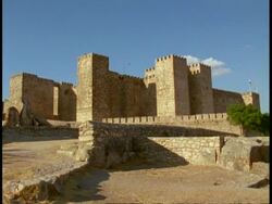 Trujillo Castle, Spain - WA castle against blue sky, cobbled street foreground Stock Footage