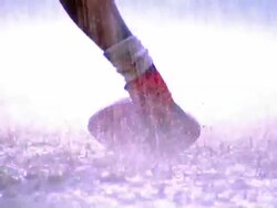 OVEREXPOSED close up PAN football player's feet walk to ball on ground then snap ball into play in rain Stock Footage