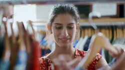 Girl looks through shirt rack in clothing shop, kisses boyfriend and poses for smartphone selfie Stock Footage