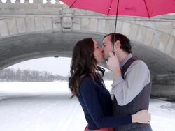 MS Young couple kissing  underneath umbrella on snowy lake during winter / Minneapolis, Minnesota, United States Stock Footage
