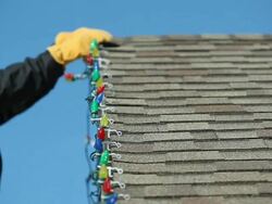Man Removing LED Christmas Lights from a House Roof Stock Footage