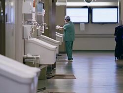 Long shot, activity in hospital operating room hallway, medical professionals walk through frame Stock Footage