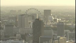 The London Eye Ferris wheel arcs above skyscrapers in London. Stock Footage