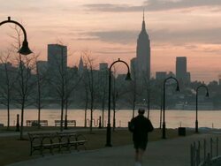 A man running on a park walkway with the Manhattan Skyline behind. Stock Footage