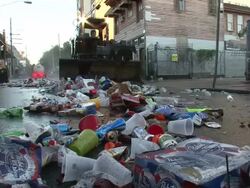 Medium Shot Low Angle - Garbage truck scooping and sweeping trash down the street / New Orleans Louisiana Stock Footage