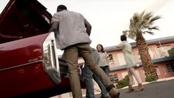 Friends arriving at Vegas motel in classic convertible unload trunk and carry luggage upstairs to room Stock Footage