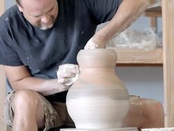 MS potter in pottery studio at pottery wheel shaping the neck of large clay vase / Palm Springs, California, USA  Stock Footage