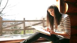 Cabin Retreat - Video of a young woman reading a book by the window. Stock Footage