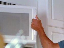 low angle PAN man taking container of food out of microwave Stock Footage
