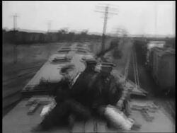 B/W 1935 3 male hobos (1 Black) sitting on top of moving train Stock Footage