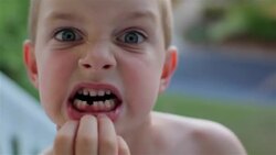 A young boy shows his missing front tooth excitedly (close-up) Stock Footage