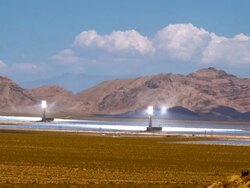 T/L ZI solar thermal power plant with thousands of heliostat mirrors directing sun light at solar receiver boilers at top of power towers in Mojave Desert across from Nevada state line  / Ivanpah Dry Lake, California, USA Stock Footage