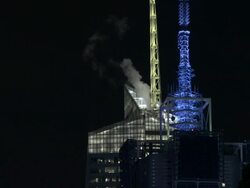Steam rising from the top of the Bank of America Building in New York City at night.  Tower are lit green and blue Stock Footage