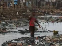 Young boy playing with paper boat in extremely polluted river, Kroo Bay, Sierra Leone, West Africa Stock Footage