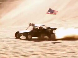 WS POV Sandrail high end rear mounted engine racing across sand dunes with flying American flag / Glamis, California, USA Stock Footage