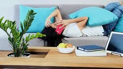 Woman speaking on mobile phone while lie down at couch Stock Footage