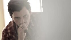 Young man seethes on motel bed as young woman paces back and forth behind him Stock Footage