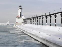 WS View of Icy water undulates near lighthouse at Lake Michigan begins to freeze / Michigan City, Indiana, United States Stock Footage