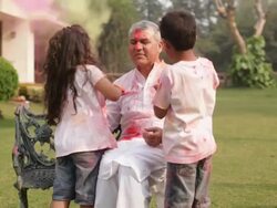 Senior man playing holi festival with his grandchildren in a lawn  Stock Footage