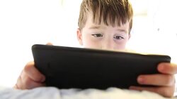 Little boy playing on tablet in bed Stock Footage