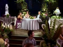 PUSH IN Bride, groom, best man, and maid of honor laughing and talking at head table Stock Footage