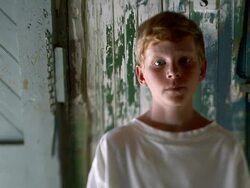 Selective rack focus medium shot redheaded boy looking serious turns toward and away from camera / Nova Scotia, Canada Stock Footage