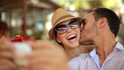 Cute Brazilian couple trade kisses and take smartphone selfies in Rio marketplace Stock Footage
