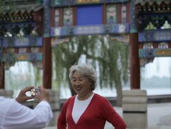 MS Mature man taking photo of elderly woman in front of traditional Chinese gate / Beijing, China Stock Footage