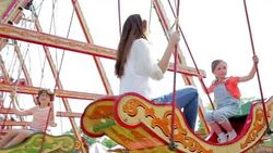 Mother and daughter riding swing at amusement park Stock Footage