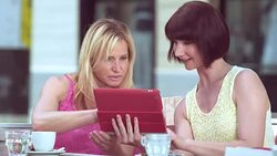 PAN Women sitting outside holding a tablet and checking clothes Stock Footage