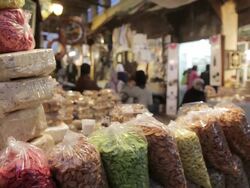MS Shot of colorful dried nuts and food, including nougat and People are seen walking past in back side in Medina lane way / Fez, Fes-Boulemane, Morocco Stock Footage