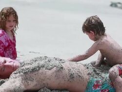 MS Man on beach covered in sand with boy sitting on top of him and girl beside him as he makes sand angels / Montezuma, Puntarenas, Costa Rica Stock Footage