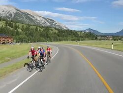 Track view of biking peloton of 4 bikers following mtn road Stock Footage