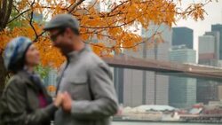 Young man pulls girlfriend in close with Brooklyn Bridge and New York skyline in background (rack-focus) Stock Footage