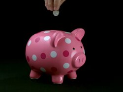 CU SLO MO Coin being dropped into slot of pink polka dot piggy bank / Studio, New Jersey, USA Stock Footage