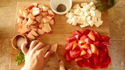 A young women preparing a Caprese salad inside of a kitchen on top of a cutting board. Stock Footage